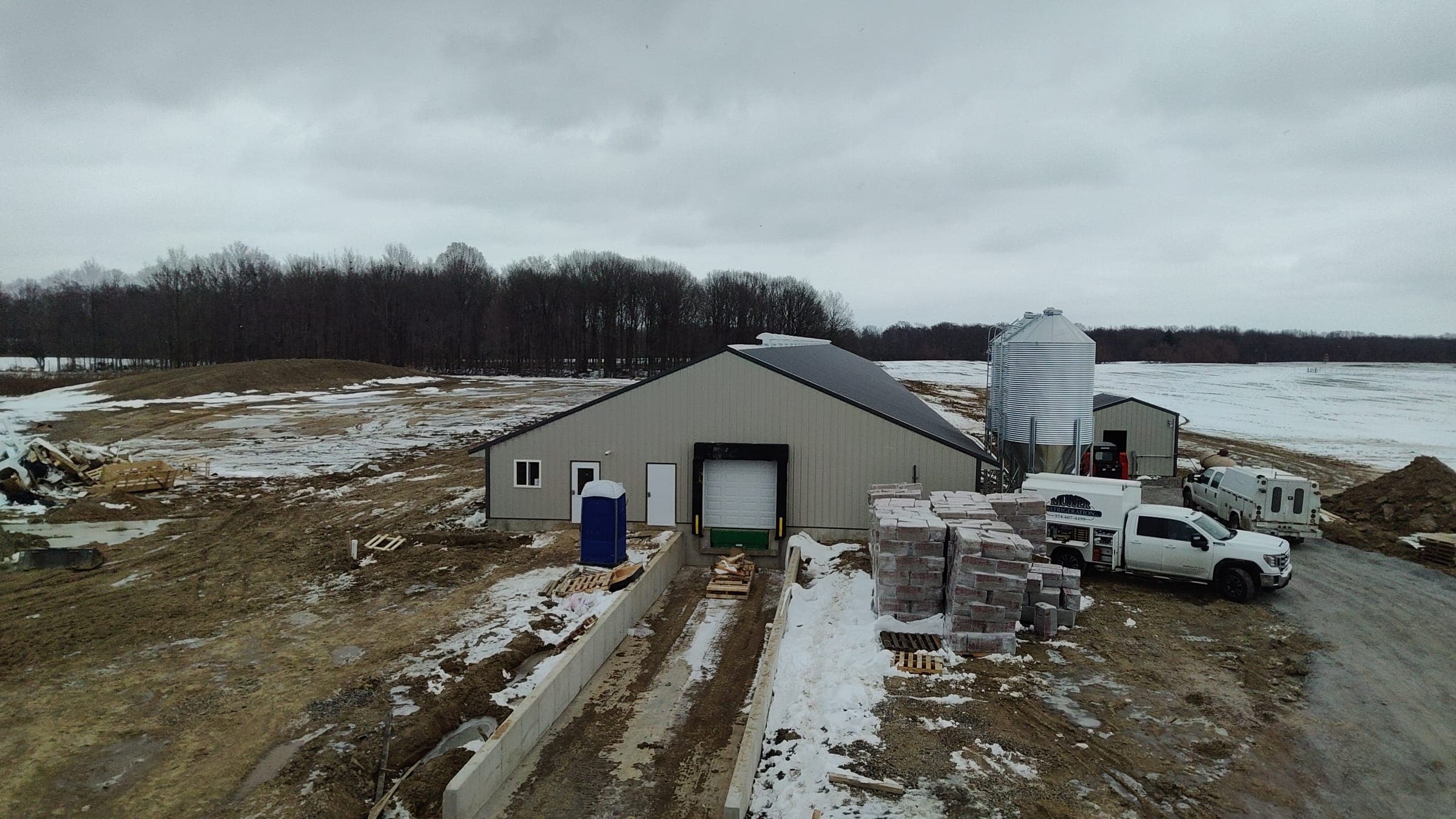 Aerial winter view of agricultural barn with feed silo and loading area built by Starlite Builders
