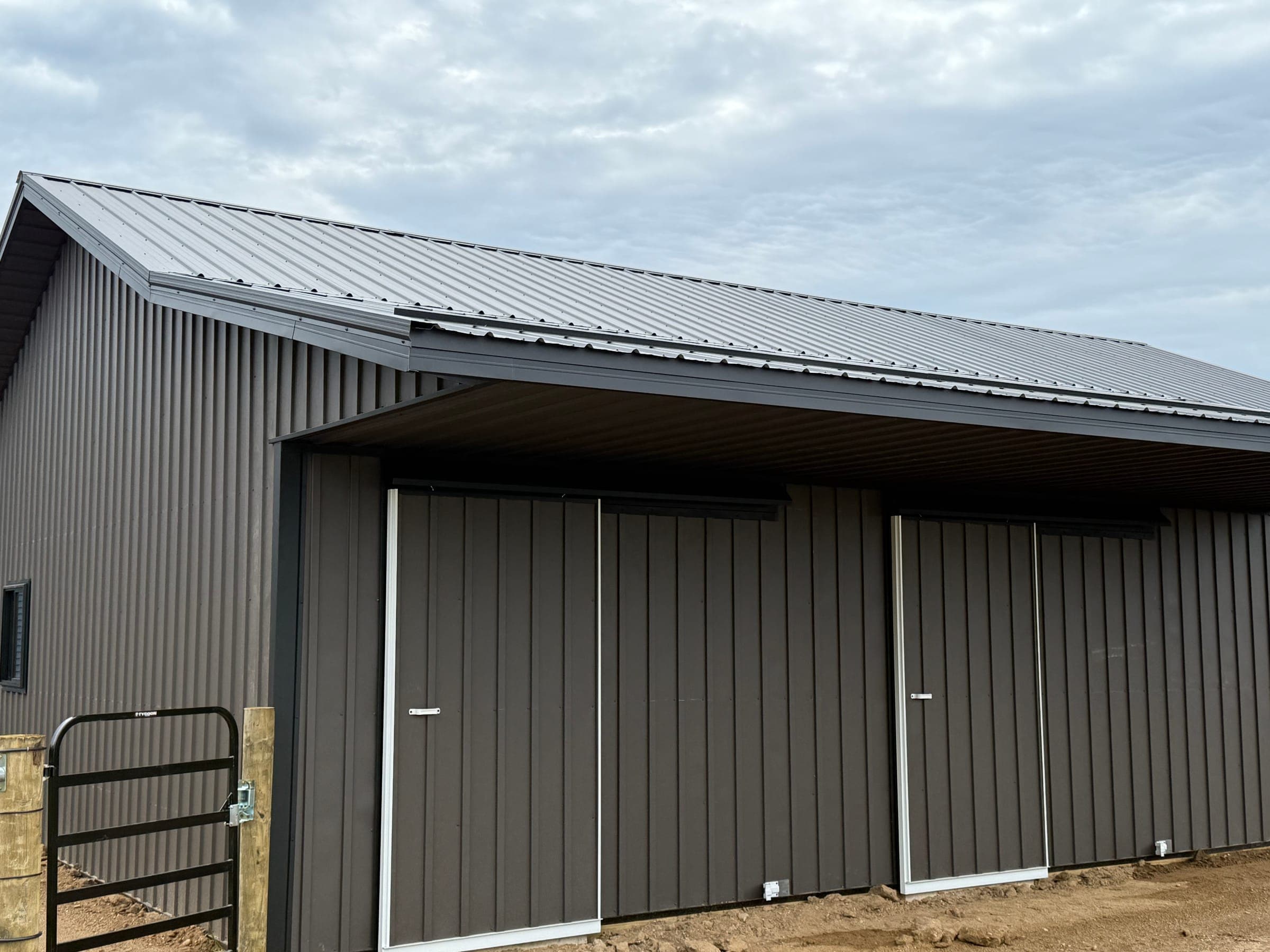 Side view of dark post-frame barn with sliding doors built by Starlite Builders