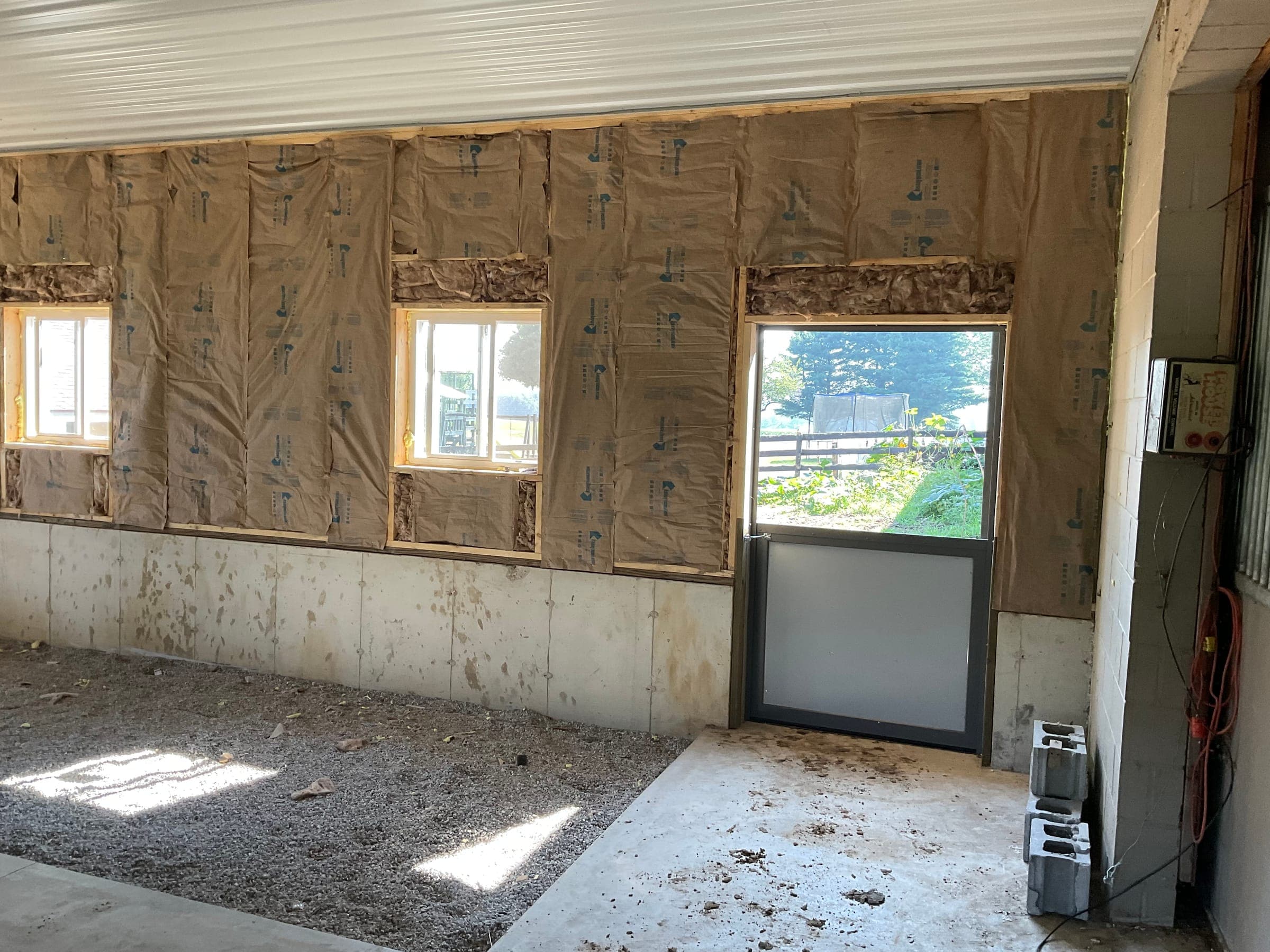 Horse barn interior under construction showing insulation and dutch door by Starlite Builders