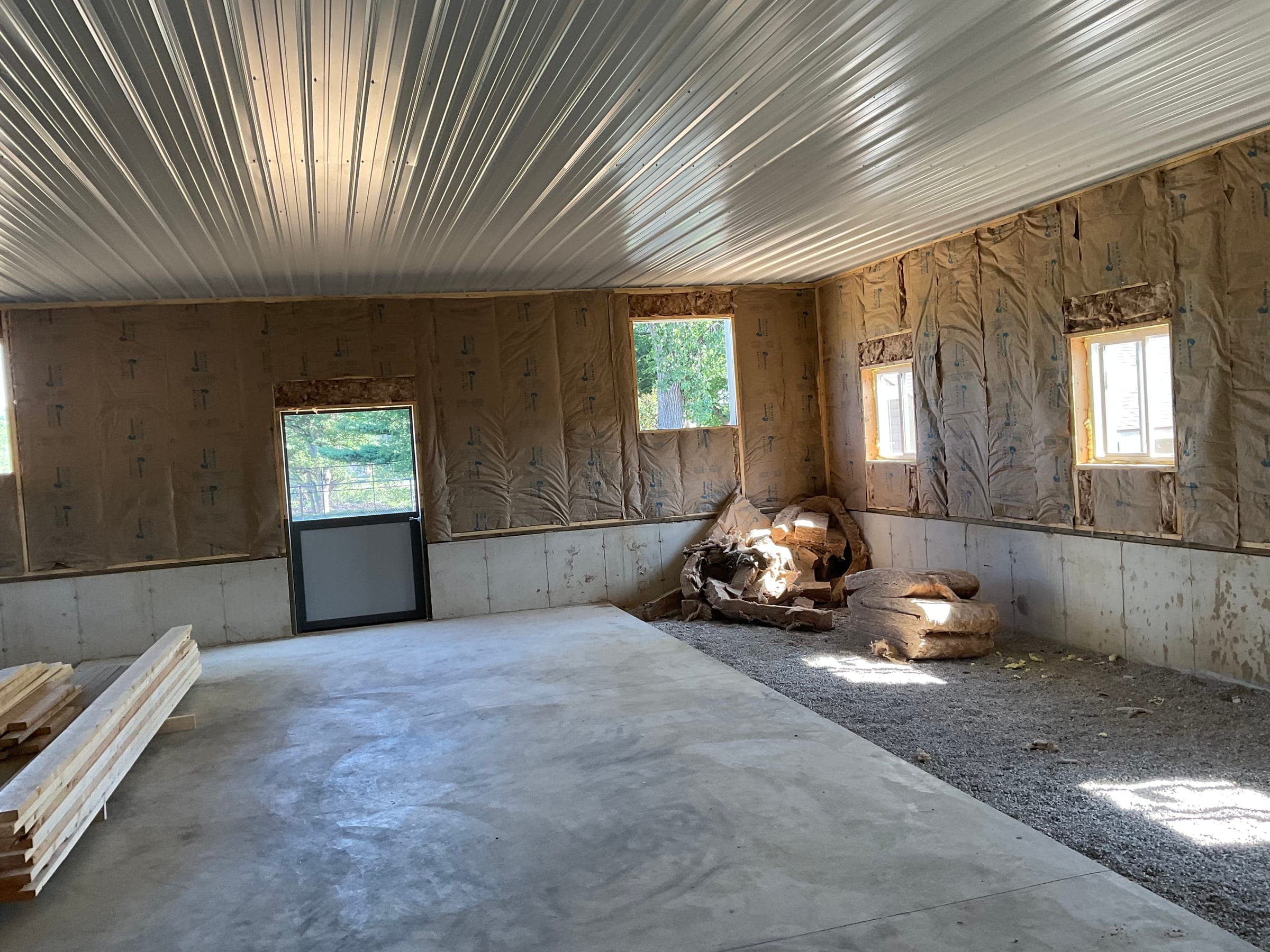 Wide interior view of horse barn with insulated walls metal ceiling and staged lumber