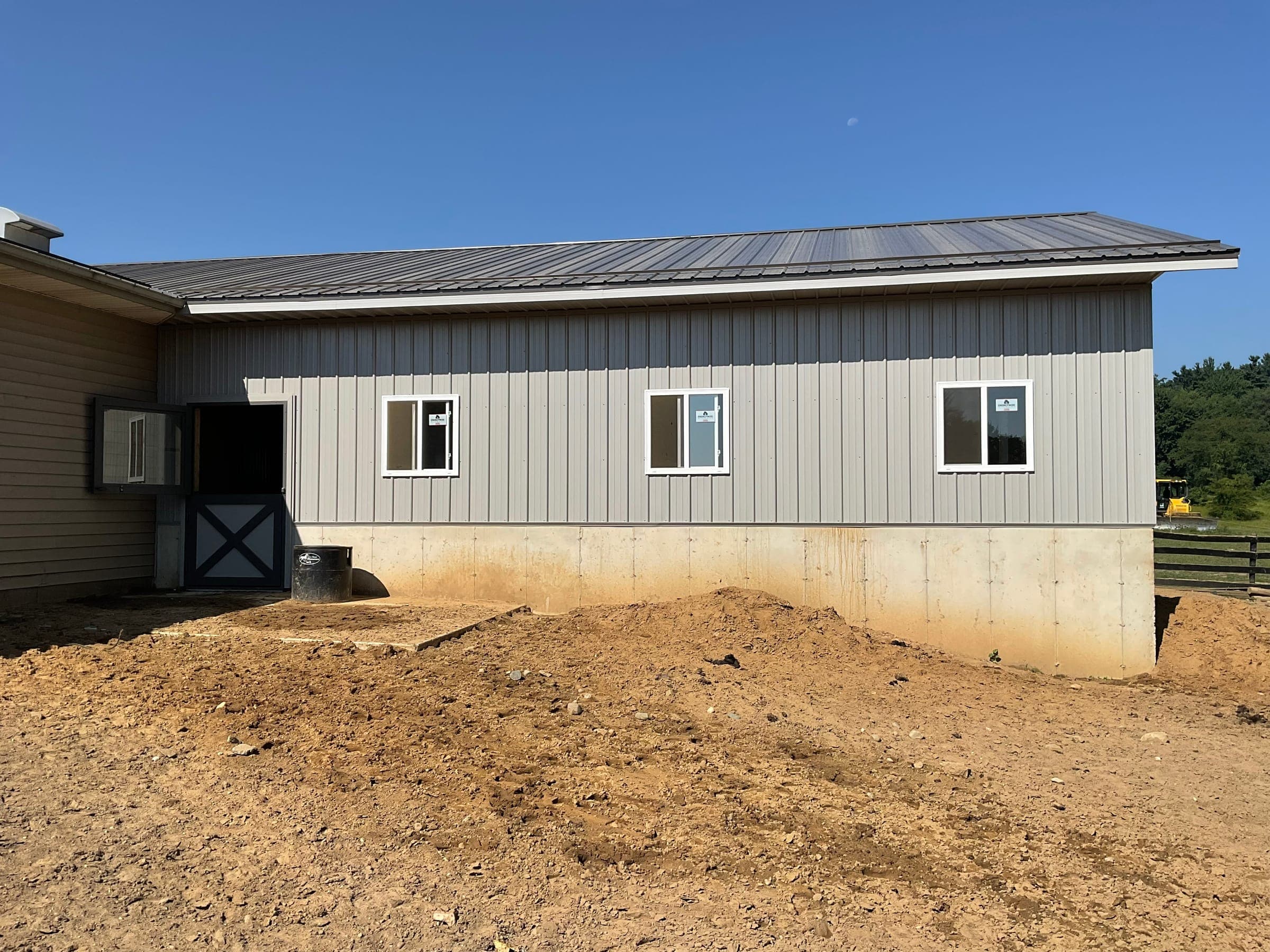 Side view of completed horse barn with metal siding and standing seam roof in Indiana
