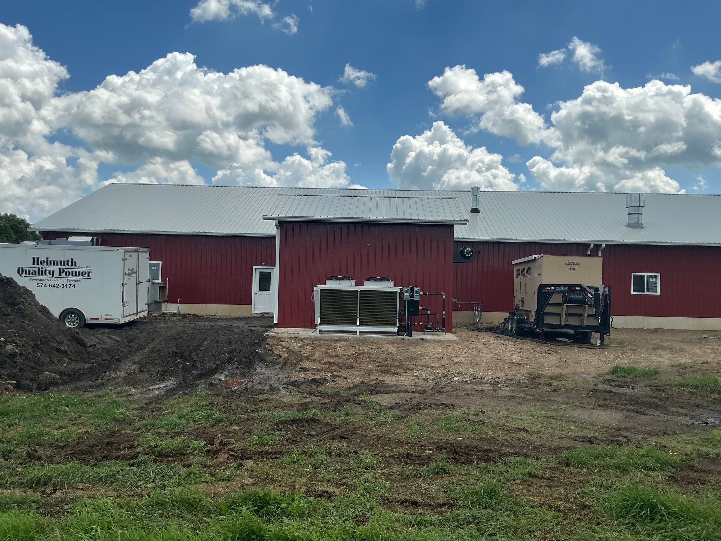 Red commercial barn rear view with generator and climate control equipment built by Starlite Builders