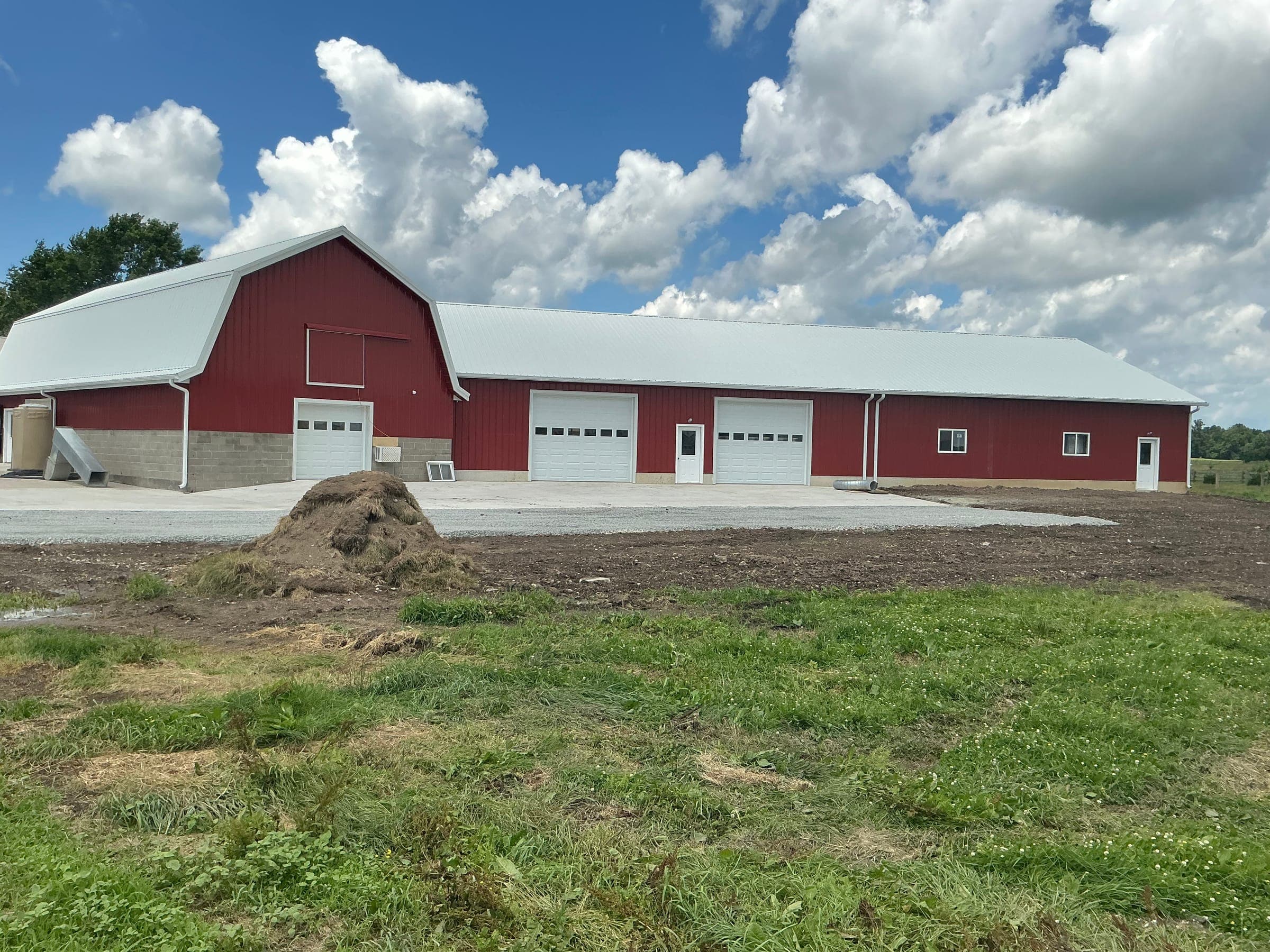 Large red commercial barn with gambrel roof and three garage bays built by Starlite Builders in Middlebury Indiana