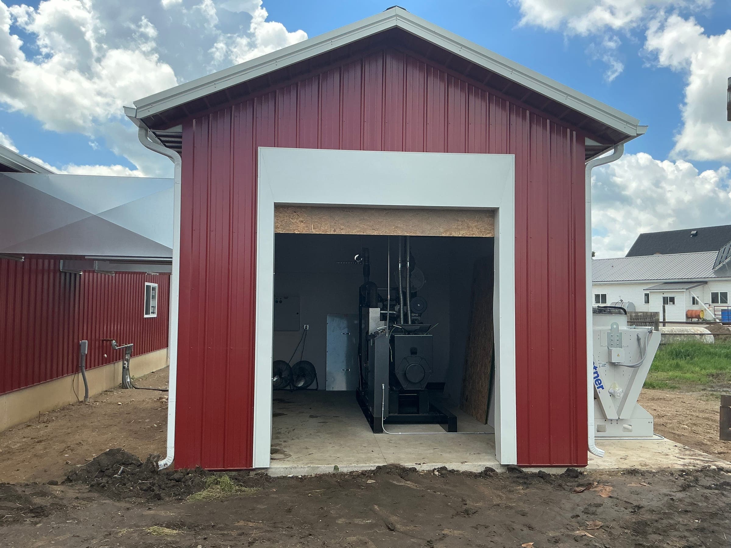 Red steel utility building with open equipment bay built by Starlite Builders on Indiana property
