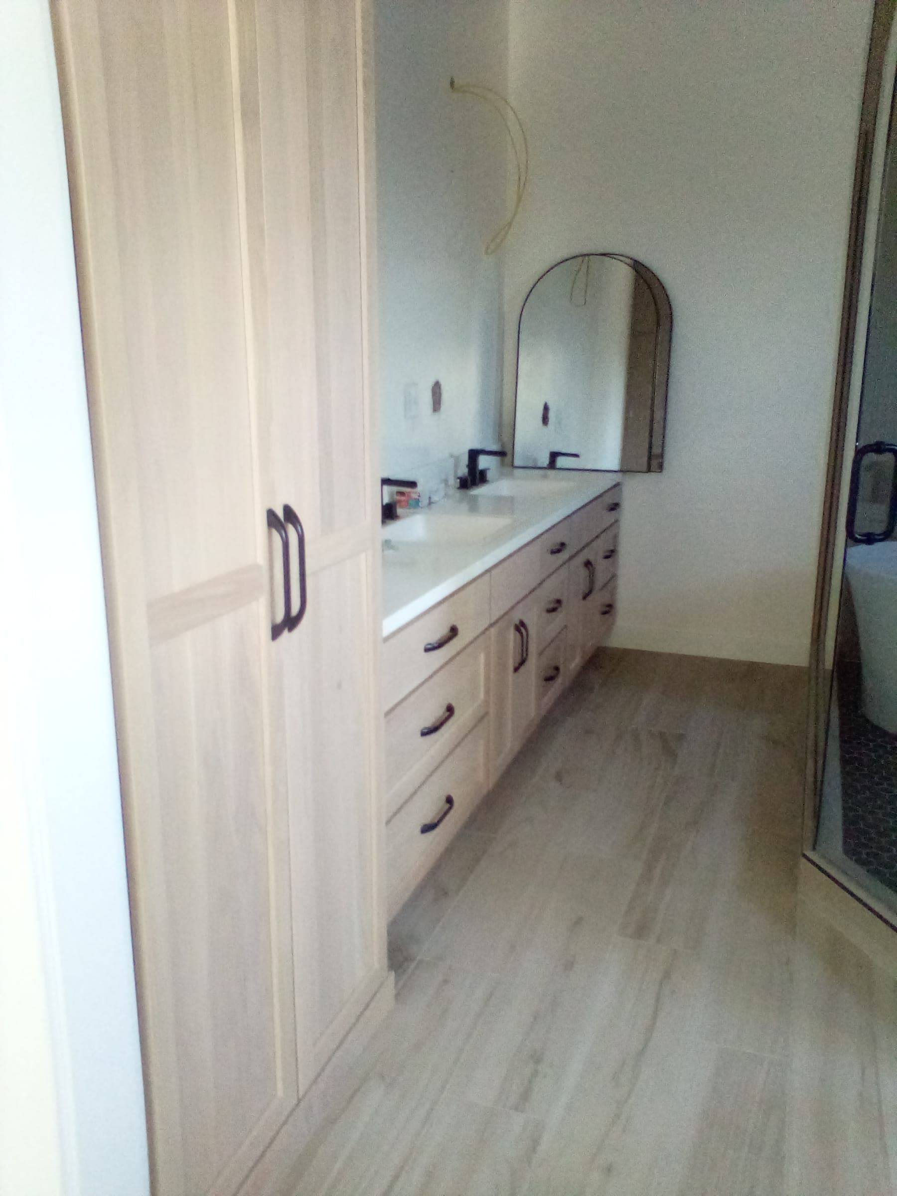 Custom bathroom vanity with light wood cabinetry and arched mirror built by Starlite Builders in Northern Indiana