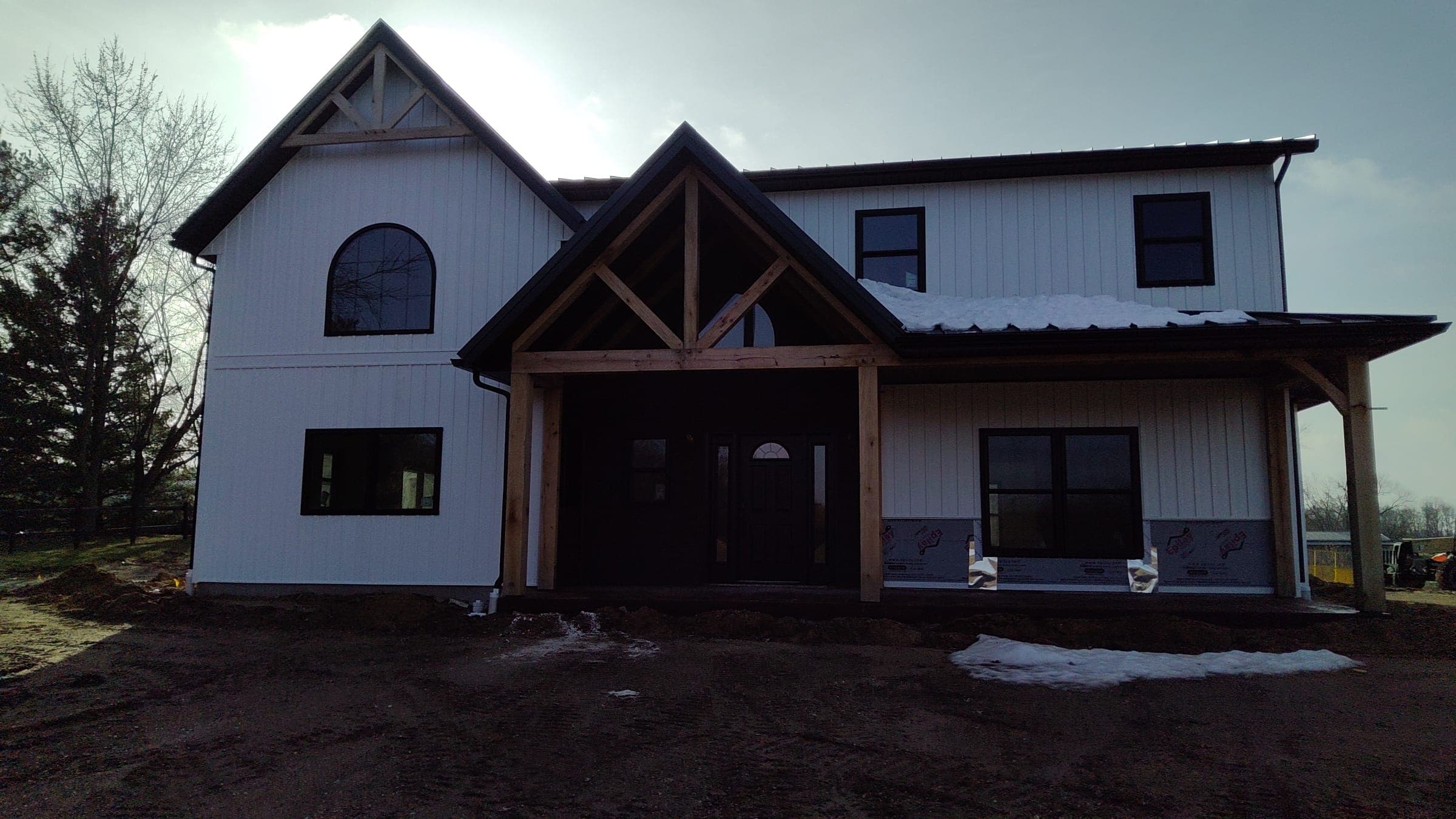White modern farmhouse with timber frame entry and arched window built by Starlite Builders