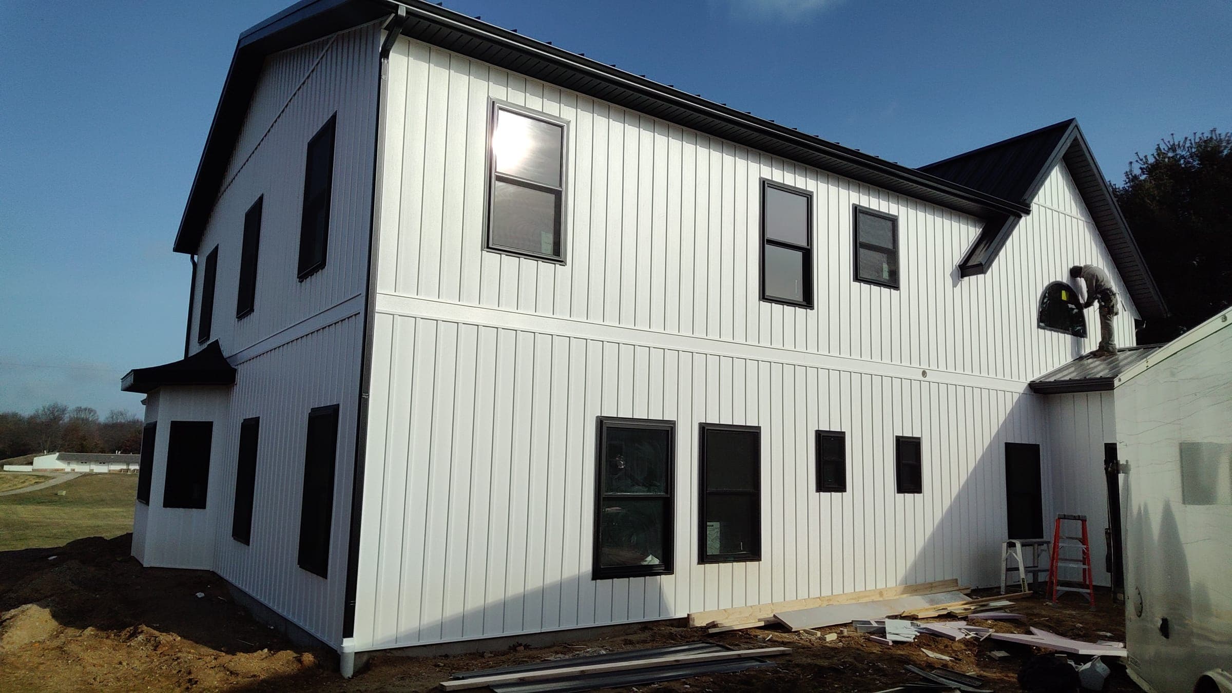 Two-story farmhouse rear elevation with board and batten siding and black window frames