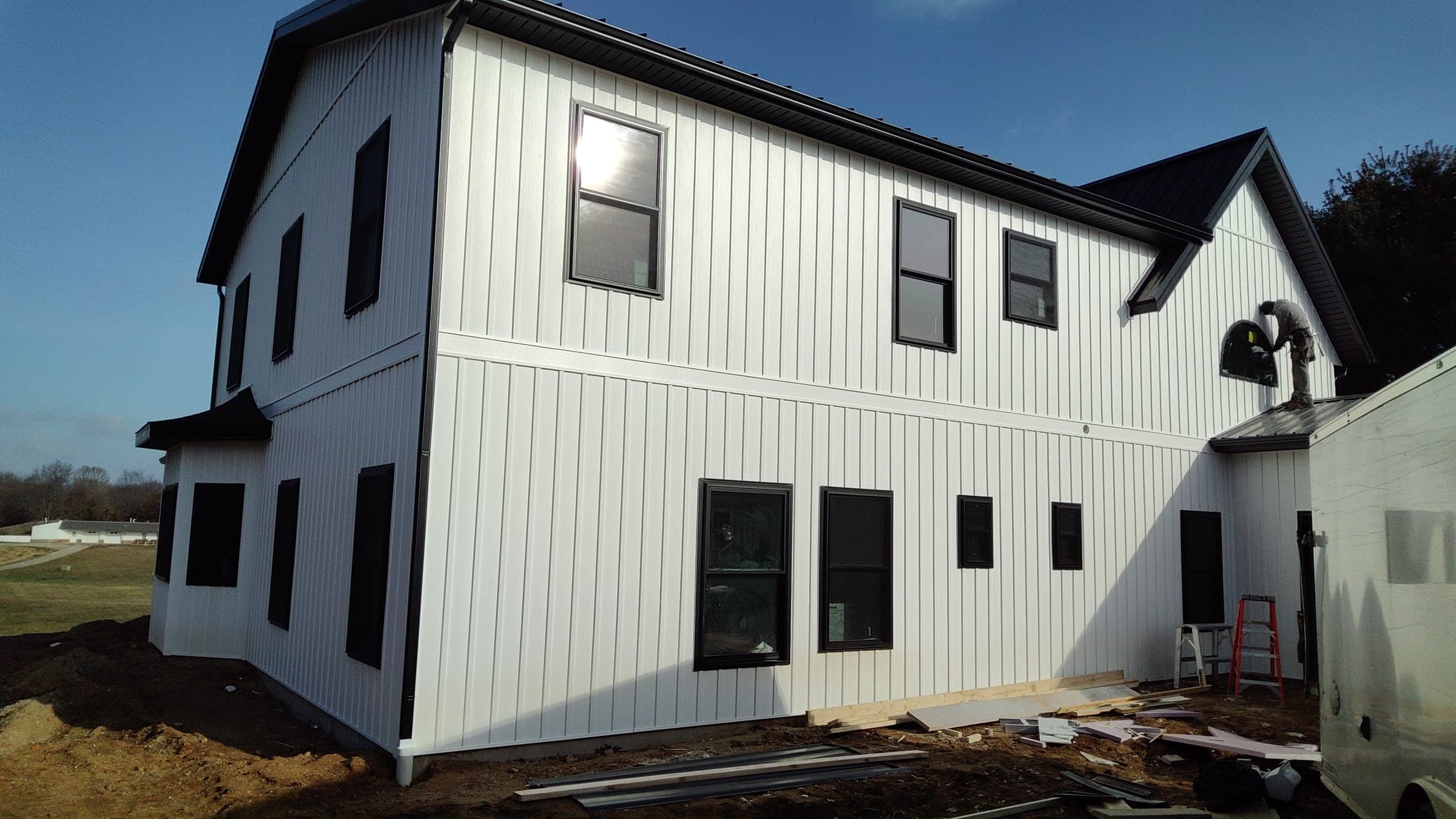Rear elevation of custom modern farmhouse with sun glare showing scale of build