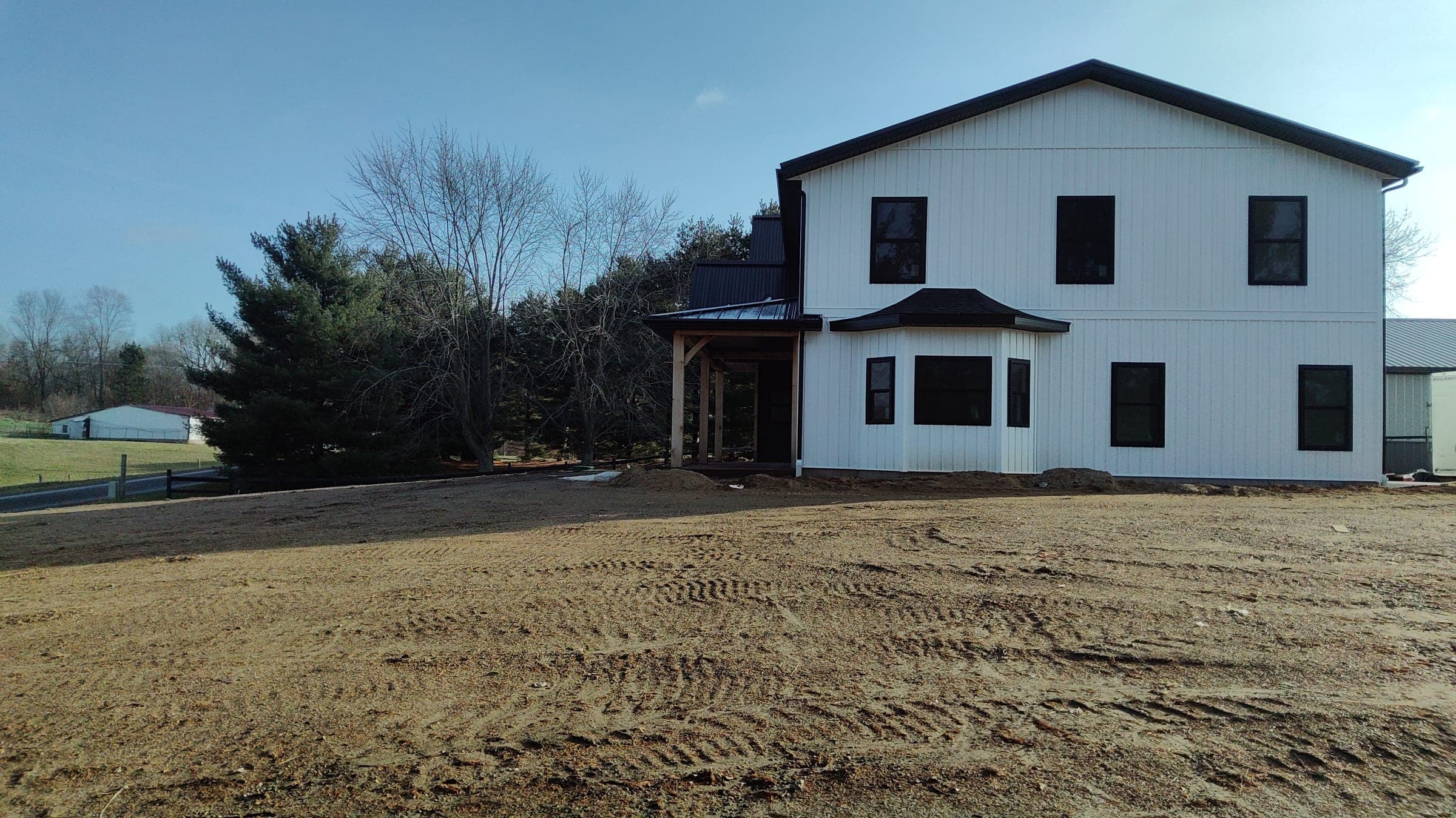 Rear side angle of custom farmhouse showing board and batten siding and black windows