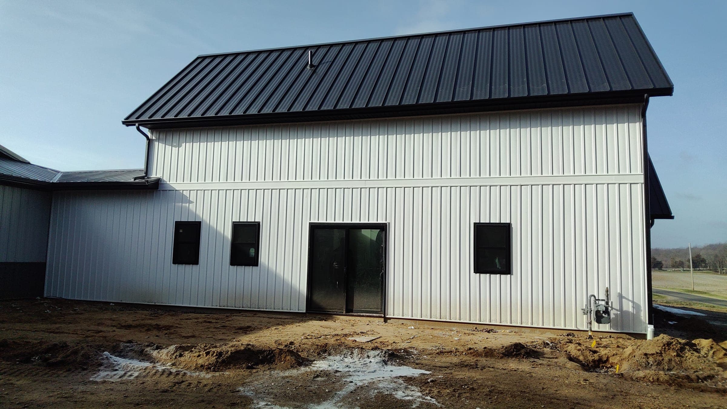 Close-up of workshop addition with standing seam metal roof on modern farmhouse