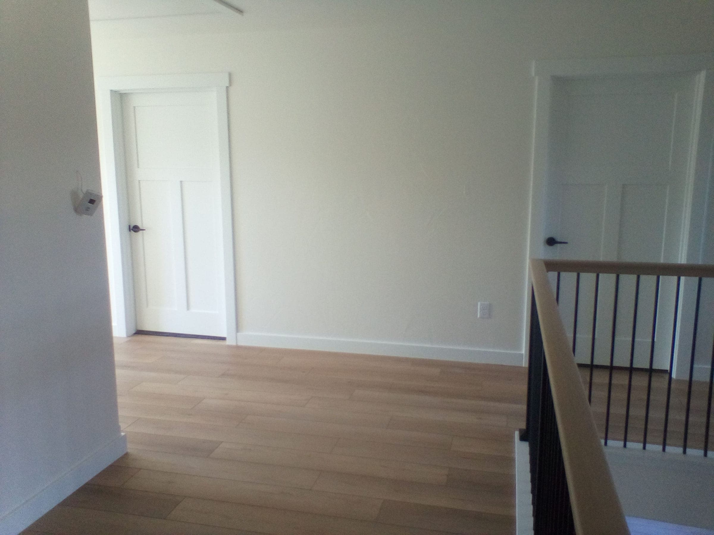 Upper landing with wood accent wall and iron railing in custom residential build