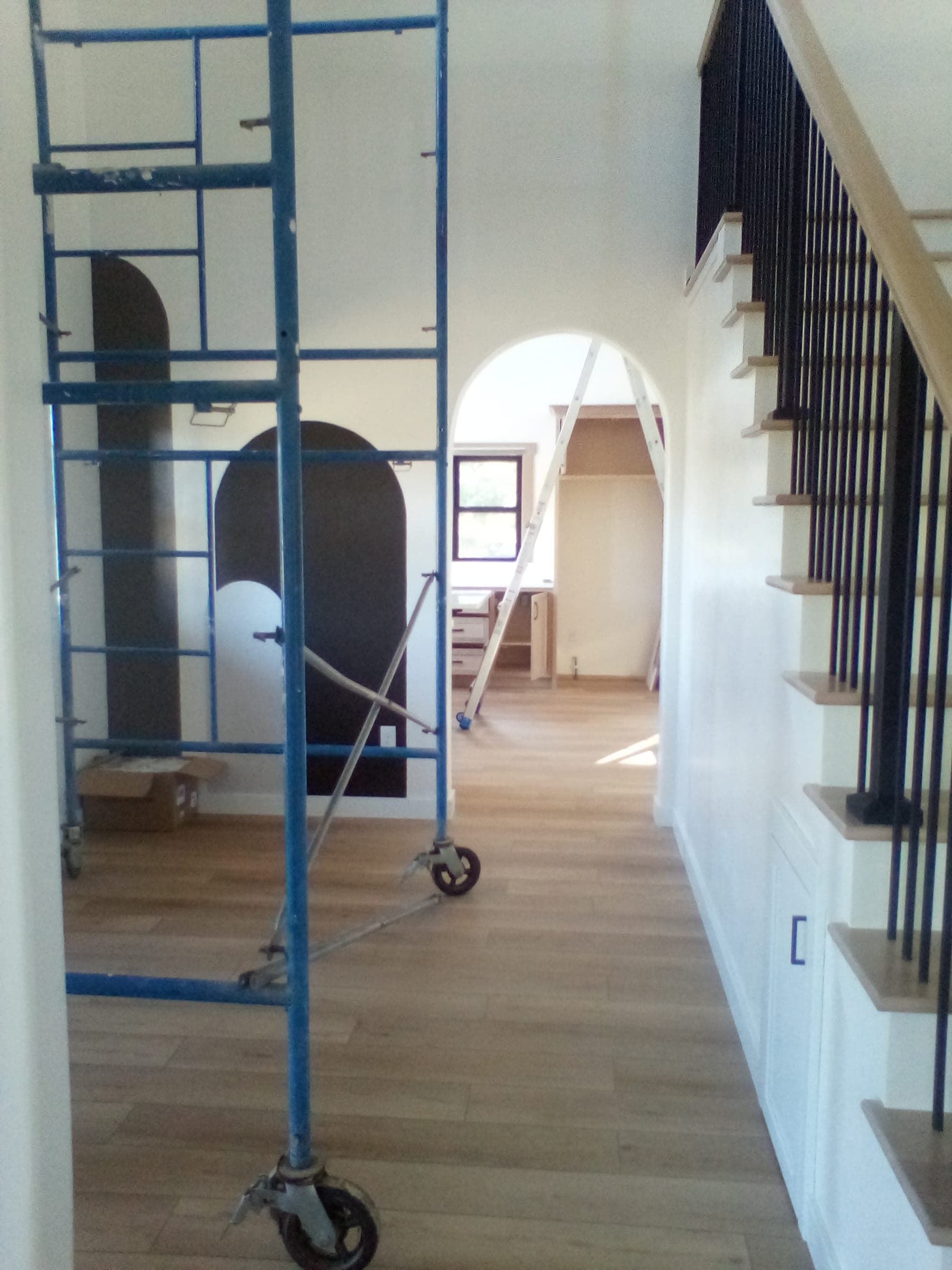 Custom staircase with iron balusters and arched doorway in residential home under construction