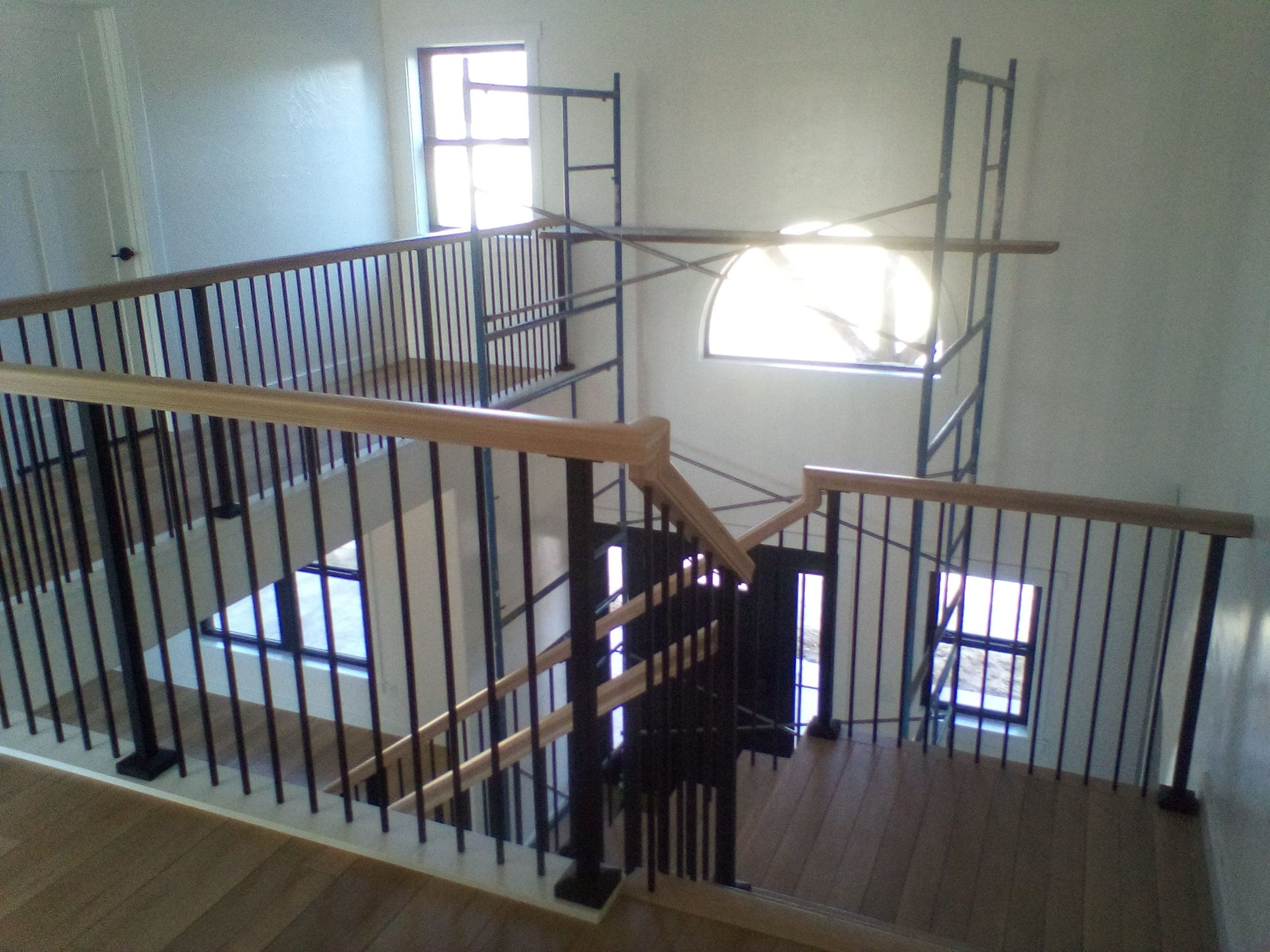Multi-story open stairwell with wood and iron railings in custom home built by Starlite Builders