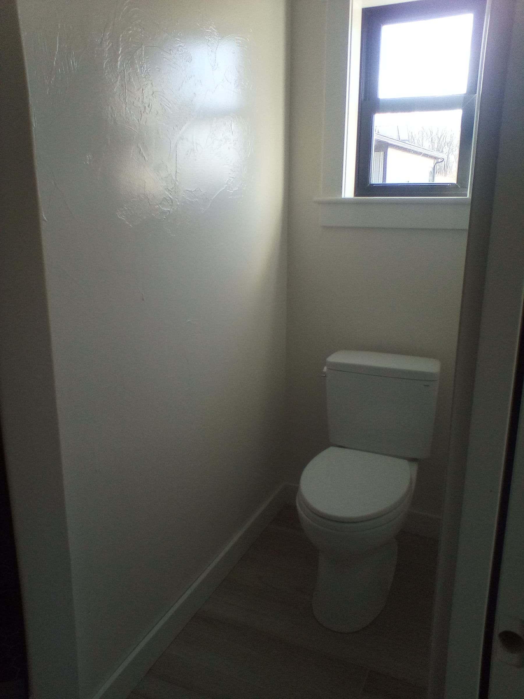 Private water closet with natural light window in custom residential build